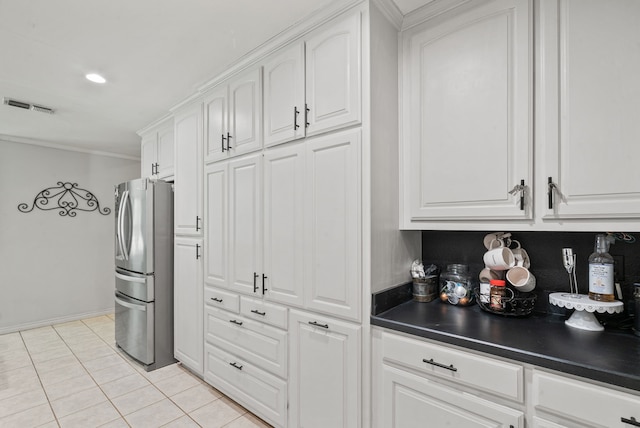 kitchen featuring light tile patterned floors, white cabinetry, stainless steel refrigerator, and ornamental molding