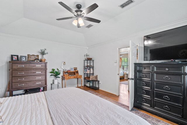 bedroom featuring lofted ceiling, a raised ceiling, ceiling fan, and light wood-type flooring