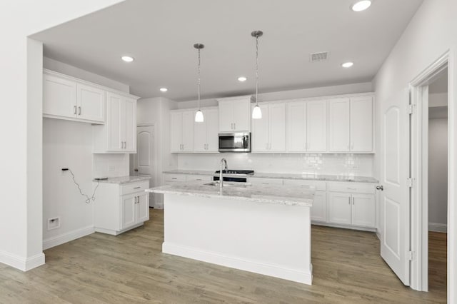 kitchen featuring a center island with sink, sink, light hardwood / wood-style flooring, hanging light fixtures, and white cabinets