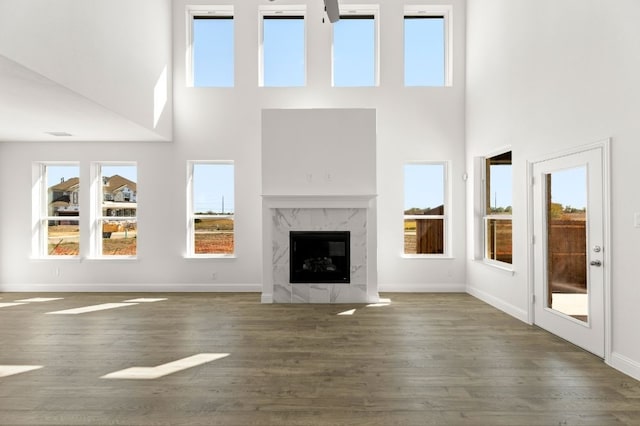 unfurnished living room featuring dark wood-type flooring, a fireplace, and a high ceiling