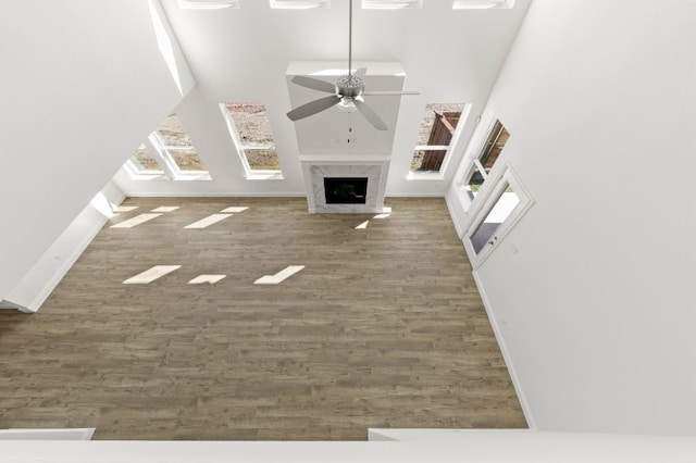 unfurnished living room featuring ceiling fan, dark hardwood / wood-style floors, a high end fireplace, and a towering ceiling