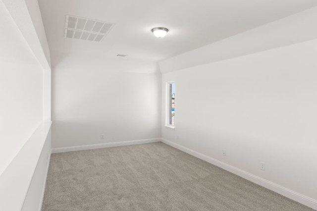 carpeted empty room featuring vaulted ceiling