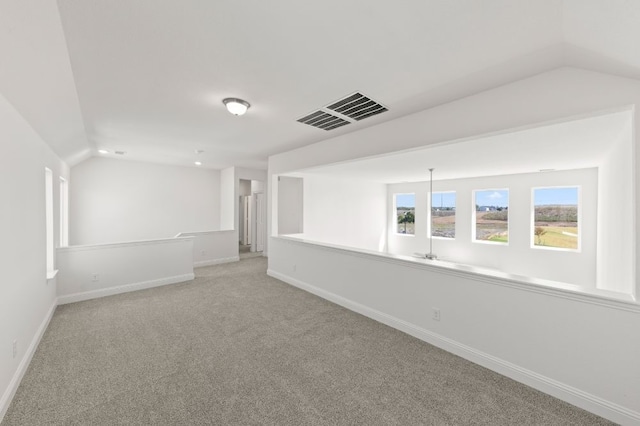 spare room featuring light carpet and lofted ceiling