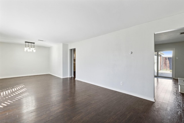 empty room featuring an inviting chandelier and dark hardwood / wood-style floors