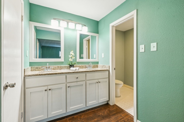 bathroom featuring toilet, hardwood / wood-style flooring, and vanity