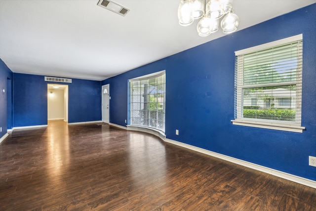 spare room featuring hardwood / wood-style flooring and a chandelier