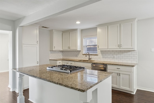 kitchen with sink, white cabinetry, stainless steel appliances, a center island, and light stone counters