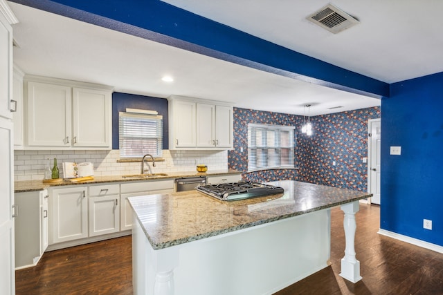 kitchen with dishwasher, a kitchen island, white cabinetry, sink, and hanging light fixtures