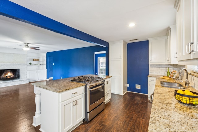 kitchen featuring light stone countertops, stainless steel gas stove, sink, and white cabinetry