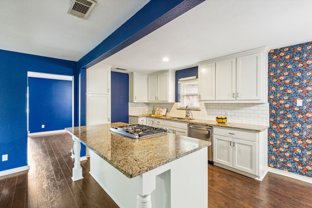 kitchen featuring a kitchen bar, light stone counters, white cabinetry, and a center island