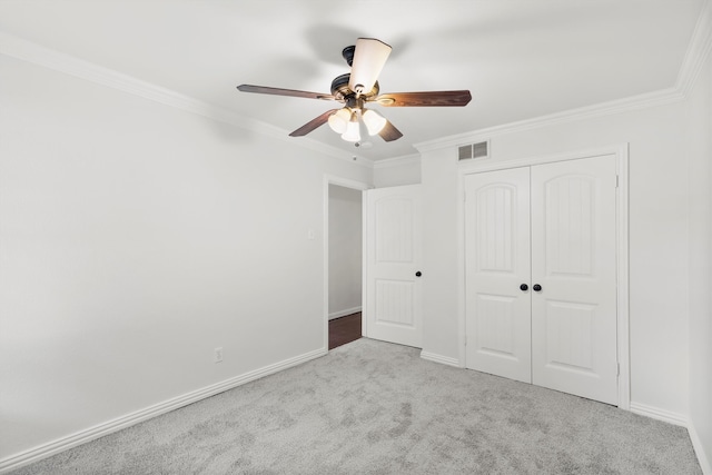 unfurnished bedroom featuring a closet, ceiling fan, light colored carpet, and crown molding