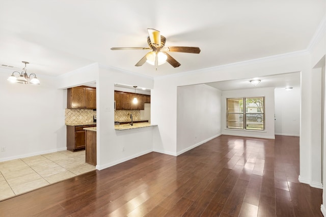 unfurnished living room with ceiling fan with notable chandelier, light hardwood / wood-style floors, and ornamental molding