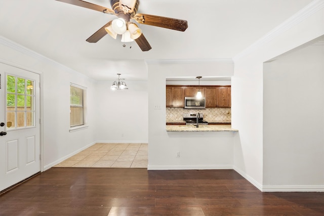 kitchen featuring ceiling fan with notable chandelier, stainless steel appliances, dark hardwood / wood-style flooring, and pendant lighting