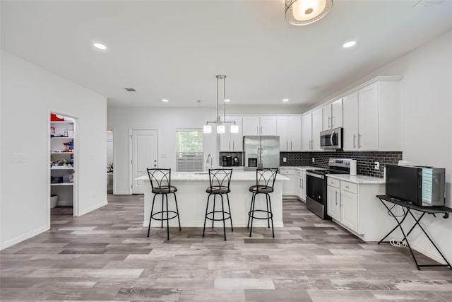 kitchen with pendant lighting, stainless steel appliances, a kitchen island, and white cabinetry