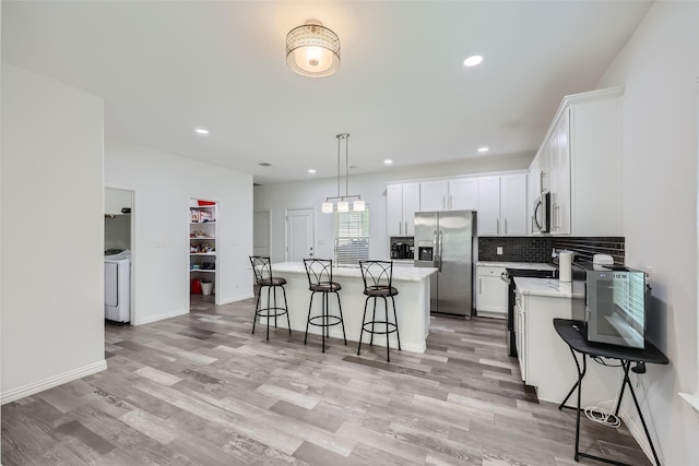 kitchen featuring hanging light fixtures, a breakfast bar area, a kitchen island, white cabinetry, and stainless steel appliances