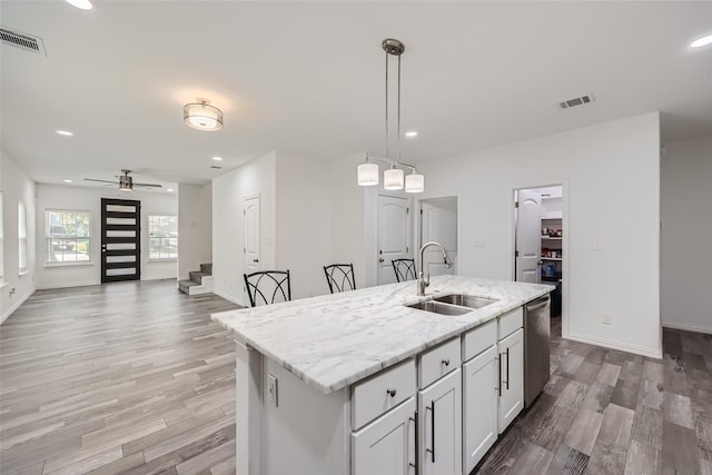 kitchen featuring ceiling fan, sink, stainless steel dishwasher, decorative light fixtures, and a kitchen island with sink