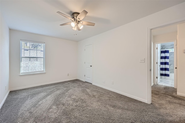 spare room featuring ceiling fan and dark carpet