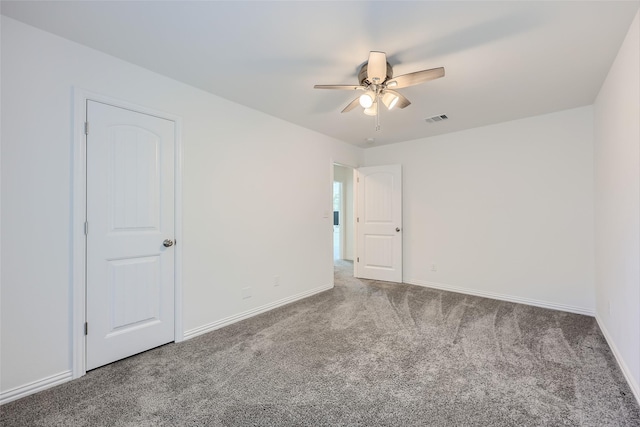 spare room featuring dark carpet and ceiling fan