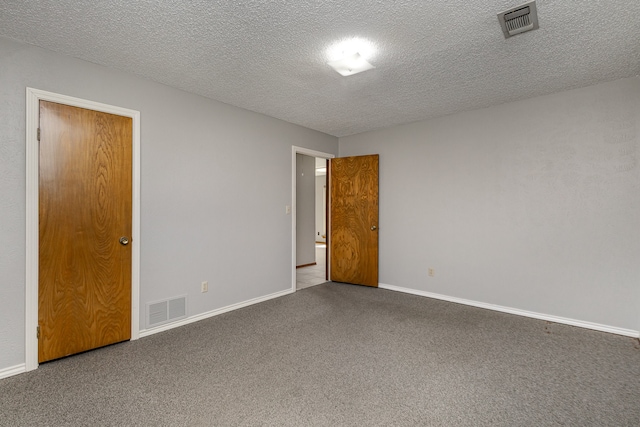 carpeted empty room featuring a textured ceiling