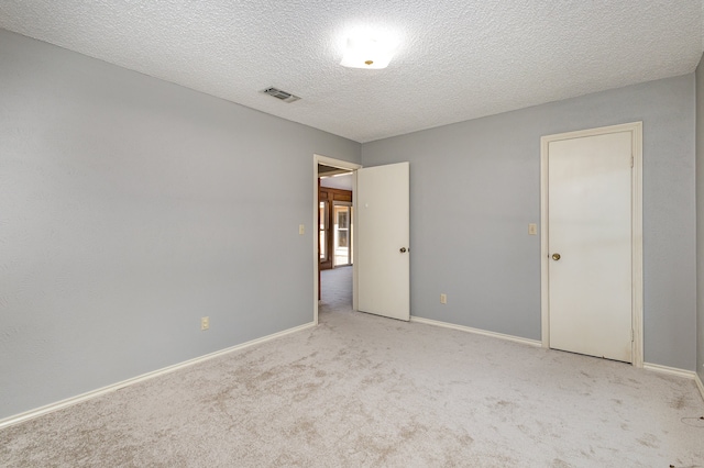 empty room featuring a textured ceiling and light carpet