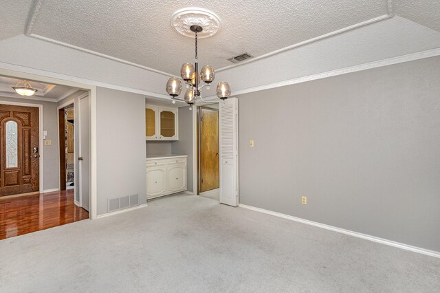 carpeted spare room featuring a chandelier, a textured ceiling, and crown molding