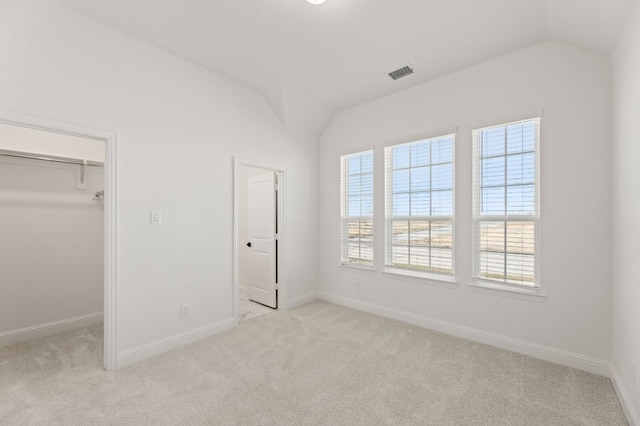 unfurnished bedroom with a closet, lofted ceiling, and light colored carpet