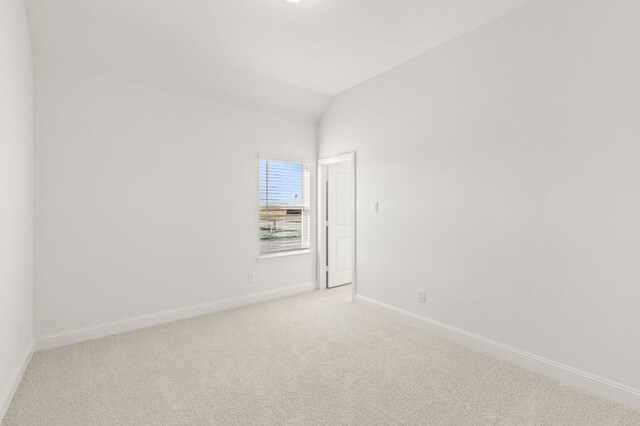 carpeted empty room with vaulted ceiling