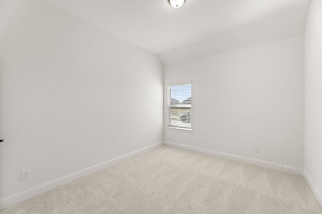 carpeted empty room featuring lofted ceiling