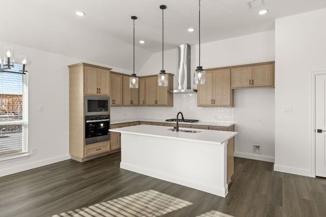 kitchen with stainless steel appliances, a kitchen island with sink, hanging light fixtures, and wall chimney range hood