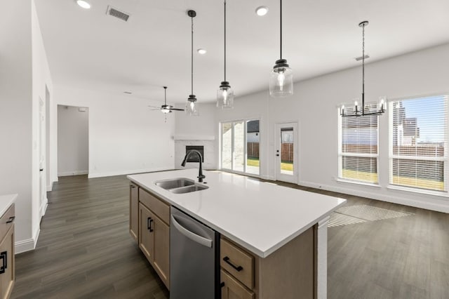 kitchen featuring stainless steel dishwasher, a kitchen island with sink, sink, and hanging light fixtures