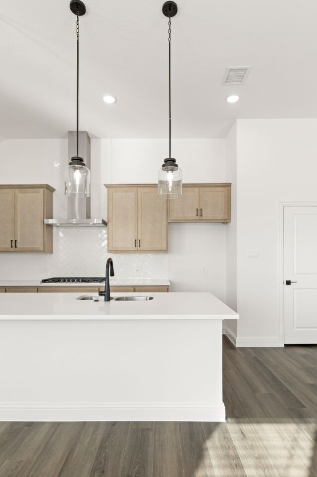 kitchen with wall chimney exhaust hood, decorative light fixtures, dark wood-type flooring, light brown cabinetry, and sink