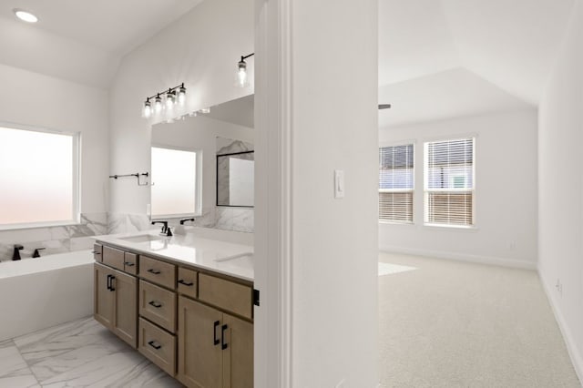 bathroom with lofted ceiling, a tub to relax in, and vanity