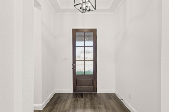 entryway featuring a tray ceiling, dark hardwood / wood-style floors, ornamental molding, and a notable chandelier