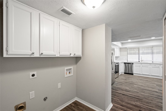 laundry area with dark hardwood / wood-style floors, washer hookup, hookup for an electric dryer, cabinets, and a textured ceiling