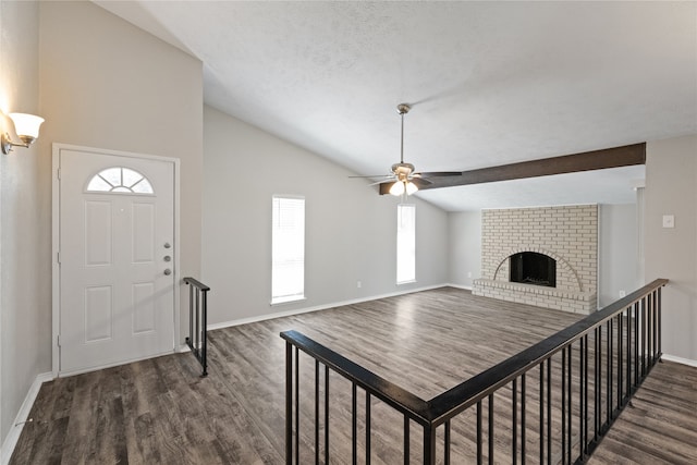 foyer entrance with lofted ceiling, a textured ceiling, dark wood-type flooring, and a brick fireplace