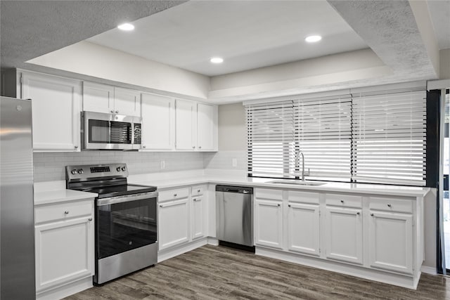 kitchen with dark hardwood / wood-style flooring, appliances with stainless steel finishes, sink, and white cabinets