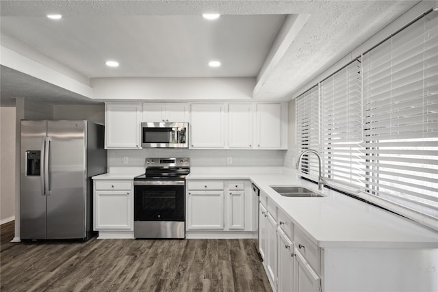 kitchen with appliances with stainless steel finishes, white cabinets, sink, and dark wood-type flooring