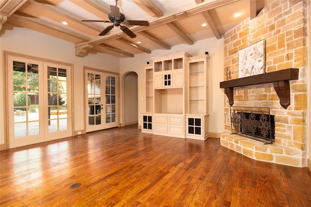 unfurnished living room featuring hardwood / wood-style floors, french doors, ceiling fan, a fireplace, and beam ceiling