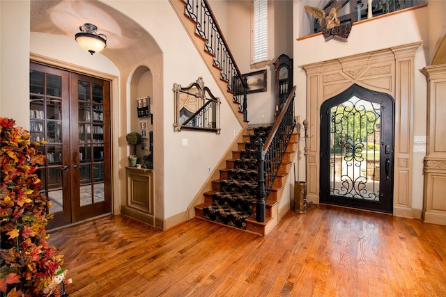 entryway with hardwood / wood-style floors, a high ceiling, and french doors