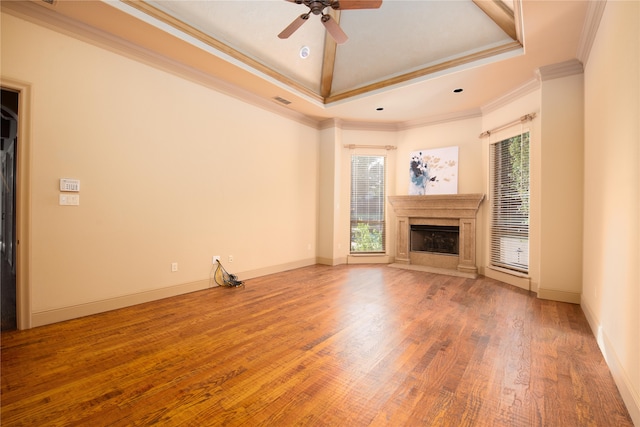 unfurnished living room featuring ornamental molding, vaulted ceiling, a raised ceiling, ceiling fan, and wood-type flooring