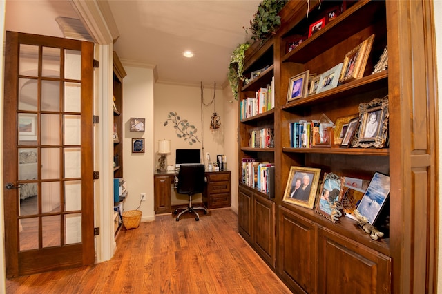 office space featuring hardwood / wood-style floors, built in desk, and ornamental molding