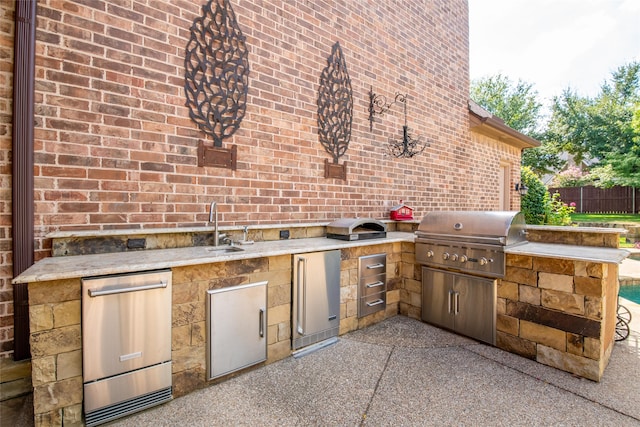 view of patio featuring sink, a grill, and exterior kitchen