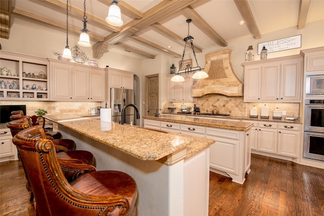 kitchen featuring premium range hood, a kitchen island with sink, and decorative light fixtures