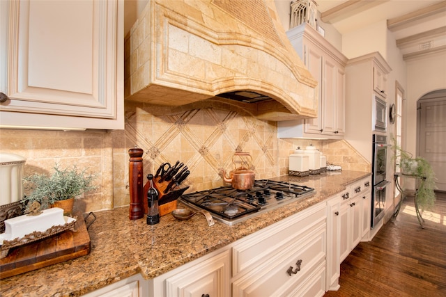 kitchen with backsplash, light stone countertops, stainless steel appliances, and dark hardwood / wood-style floors