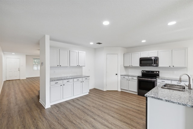 kitchen with light stone counters, sink, white cabinets, light hardwood / wood-style flooring, and appliances with stainless steel finishes