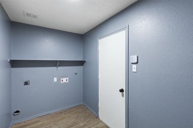 washroom featuring light hardwood / wood-style floors, washer hookup, hookup for an electric dryer, a textured ceiling, and hookup for a gas dryer