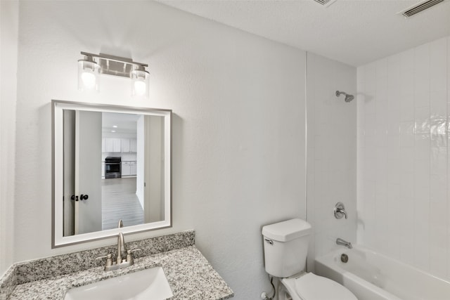 full bathroom featuring a textured ceiling, tiled shower / bath combo, vanity, and toilet