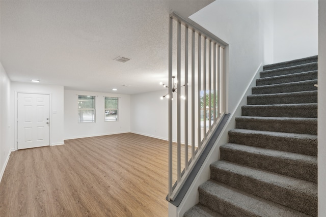 stairway with wood-type flooring and a textured ceiling