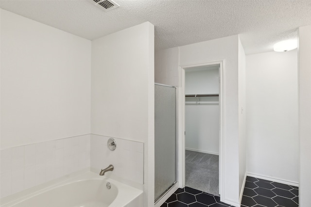 bathroom featuring a textured ceiling, independent shower and bath, and tile patterned flooring