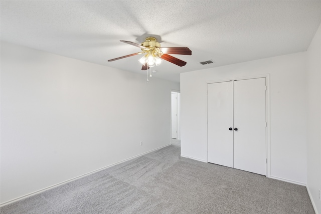 unfurnished bedroom featuring ceiling fan, carpet floors, a closet, and a textured ceiling